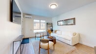 Located at 1569 Oak St in Columbus, Ohio, this well-appointed 2-bedroom, 2-bathroom residence offers a thoughtfully designed single-floor layout. The open-concept kitchen and living area serves as the heart of the home, featuring light wood-tone cabinetry, stainless steel appliances, and a large central island with a dark quartz countertop and built-in sink — ideal for both meal prep and casual dining. Wood-look flooring runs throughout, tying the spaces together with a warm, cohesive aesthetic. The living area is bright and welcoming, with natural light streaming through large windows that frame views of the surroundings, complemented by a wall-mounted mini-split system for efficient climate control. The primary bedroom offers multiple windows, generous closet space, and a tranquil ambiance, while the second bedroom provides comfortable accommodations with patio access. Both bathrooms are finished in a clean, modern style — one featuring a floating vanity with matte black fixtures and a soaking tub with bold dark wall panels. Additional highlights include a dedicated laundry area, utility room, four closets, a hallway, and two private patios that extend the living space outdoors.