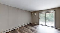 Located at 1800 Park West Blvd in Griffith, Indiana, this two-bedroom, two-bathroom residence offers a practical and well-organized single-floor layout. The combined living and dining area serves as the heart of the home, featuring rich wood-style plank flooring, neutral taupe walls, a ceiling fan, and a sliding glass door that floods the space with natural light and provides views of surrounding greenery. Baseboard heating and a wall-mounted A/C unit ensure year-round comfort throughout the living areas.

The galley-style kitchen is outfitted with bold dark cabinetry, white countertops, a stainless steel sink, and black appliances including a range and refrigerator, creating a striking contrast that adds visual interest to the functional space. Wood-style flooring continues throughout the kitchen for a cohesive look.

Both bedrooms feature plush neutral carpeting, individual windows with blinds for natural light and privacy, and wall-mounted A/C units with baseboard heating. The primary bedroom offers a comfortable, well-proportioned retreat.

The two bathrooms are finished with clean white square tile surrounds and full tub-shower combinations, maintaining a bright and functional aesthetic. A dedicated closet adds practical storage to complete this straightforward and comfortable residence.