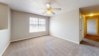 Located at 13900 S Peoria Ave in Glenpool, Oklahoma, this 2-bedroom, 2-bathroom residence offers a well-organized single-floor layout designed for comfortable everyday living. The kitchen is equipped with light wood cabinetry, a double sink, tile flooring, and white appliances including a refrigerator, range, and microwave. A peninsula counter opens toward the living area, where a pendant light fixture and plush carpet create a warm, inviting atmosphere. The second kitchen area provides additional counter space and storage, adding to the unit's overall functionality. Both bedrooms feature soft carpeting, neutral wall tones, ceiling fans with light fixtures, and windows that allow natural light to filter in. The primary bedroom is generously sized and includes a dedicated walk-in closet outfitted with wire shelving for organized storage. The two bathrooms are finished with light tile flooring and light wood vanities with countertop sinks. One bathroom features a full tub-shower combination, while the other offers a vanity with ample cabinet storage. Textured ceilings are present throughout, and a staircase is also included within the space. The overall aesthetic is clean and neutral, providing a functional and move-in-ready environment.