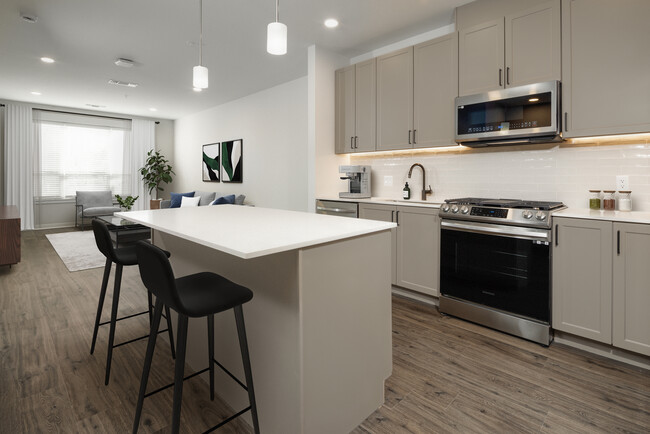 Kitchen with stainless steel appliances, quartz countertops, tile backsplash, grey cabinetry, and hard surface flooring (representative imagery) - Avalon Princeton on Harrison