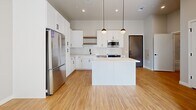 Located at 7831 E Union Ave in Denver, Colorado, this thoughtfully designed one-bedroom, one-bathroom residence offers a clean, modern aesthetic throughout its efficiently utilized single floor. The open-concept kitchen serves as the heart of the home, showcasing white shaker cabinetry, a classic subway tile backsplash, sleek light-colored countertops, and a full suite of stainless steel appliances including a refrigerator, range, and built-in microwave. A central island with pendant globe lighting above adds both functional prep space and a stylish focal point, while warm-toned hardwood-style flooring runs throughout the main living areas. The bedroom is a calm, light-filled retreat featuring plush carpeting, tall ceilings, and large windows that frame views of the Denver skyline, allowing abundant natural light to pour in. A dedicated closet provides organized storage. The full bathroom continues the modern design language with a white vanity, large framed mirror, and a tub-shower combo adorned with marble-look tile surround. Additional conveniences include an in-unit laundry area and a utility room. The overall ambiance is bright, clean, and contemporary, making for a polished urban living experience.
