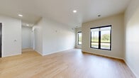 Located at 582 Larson Orchard Pky in Hobart, WI, this thoughtfully designed single-floor home offers three bedrooms and two bathrooms across a well-utilized floor plan. The modern kitchen serves as a central highlight, featuring dark gray shaker-style cabinetry, a white center island with pendant lighting, stainless steel appliances including a refrigerator, range, microwave, and dishwasher, and light hardwood-style flooring that extends into the adjoining living area. Large black-framed windows in the living and bedroom areas invite generous natural light and offer pleasant outdoor views of the surrounding greenery. The primary bedroom provides a comfortable retreat, complemented by a walk-in closet with wire shelving. Additional bedrooms are carpeted and bright, each with black-framed windows overlooking the outdoors. The two bathrooms are finished in a clean, contemporary style — one featuring a walk-in shower with matte black fixtures and a dark vanity with a white countertop, and the other offering a full tub-shower combination with matching matte black hardware and a similarly styled vanity. Neutral tones, clean lines, and consistent modern finishes give the home a cohesive and move-in-ready aesthetic throughout.