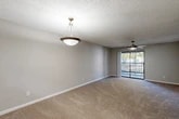 Located at 6710 Collins Road in Jacksonville, FL, this single-floor, 2-bedroom, 2-bathroom residence offers a functional and comfortable layout. The open-concept living, dining, and kitchen area serves as the heart of the home, with plush carpeting underfoot, a ceiling fan overhead, and a pendant light above the dining space. A sliding glass door connects the living area to a private balcony, bringing in natural light and outdoor views. The kitchen is well-appointed with light wood cabinetry, white subway tile backsplash, light stone countertops, black appliances including a range, refrigerator, and dishwasher, plus wood-look vinyl flooring. A hallway leads to both bedrooms, each featuring soft carpet, ceiling fans, and ample closet space with bifold doors. The primary bedroom includes a sliding glass door to the balcony, while the second bedroom offers a window with natural light. Both bathrooms are finished with wood-look vinyl flooring, light wood vanities with stone countertops, and tiled shower-tub combinations. The unit also includes a dedicated laundry area and utility room, along with four closets providing generous storage throughout.