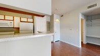 This efficient single-floor residence offers a thoughtfully laid-out floor plan encompassing a combined kitchen and living area, one bedroom, one bathroom, a closet, and a hallway. Warm hardwood-style flooring runs consistently throughout the entire unit, lending a cohesive and inviting feel to every room.

The open-concept living area is bright and airy, featuring vaulted ceilings, a ceiling fan, and a sliding glass door that opens to a private balcony with outdoor views, allowing natural light to fill the space. The kitchen is positioned adjacent to the living area, separated by a raised breakfast bar with a light-toned countertop. It includes white cabinetry with wood-tone accents, a double-basin sink, a dishwasher, a range with oven, and a full-sized refrigerator. Open glass shelving provides additional storage and display space.

The bedroom is comfortably sized, offering two windows that invite natural light and include blinds for privacy, along with a ceiling fan overhead. The bathroom features a wide vanity with ample counter space and under-cabinet storage, a Hollywood-style light bar above a large mirror, and a separate tub and shower combination. A dedicated closet and hallway complete the layout, ensuring practical storage and smooth flow throughout the residence.