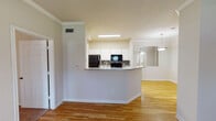 Located at 1201 Dulles Avenue in Stafford, Texas, this single-floor residence offers a well-designed layout with a blend of hardwood and carpeted flooring throughout. The open-concept living and dining area is defined by elegant crown molding, decorative columns, and warm hardwood floors that extend seamlessly through the main living spaces. Natural light filters in through large windows fitted with blinds, creating a bright and welcoming ambiance.

The kitchen is equipped with white cabinetry, a tiled backsplash, granite-style countertops, and black appliances including a refrigerator, range, and built-in microwave. A breakfast bar connects the kitchen to the dining area, which is complemented by a pendant light fixture and mirrored wall panels that visually expand the space.

The bedrooms feature plush carpeting, ceiling fans, and windows that bring in natural light. The primary bathroom includes a full tub-shower combination, a granite-topped vanity, mirrored sliding closet doors, and hardwood flooring. A second bathroom offers a similarly appointed vanity with granite countertops and hardwood floors, providing a clean and functional space. Throughout the unit, neutral wall tones and consistent finishes contribute to a cohesive and move-in-ready aesthetic.