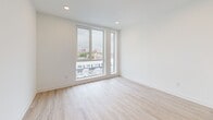 Located on the sixth floor at 1635 N Fifth St in Philadelphia, PA, this well-appointed one-bedroom, one-bathroom unit offers a thoughtfully designed open-concept layout with clean, contemporary finishes throughout. Light wood-tone luxury vinyl flooring runs seamlessly across the entire unit, complementing the bright white walls and recessed lighting that create an airy, modern atmosphere.

The combined kitchen and living area serves as the heart of the unit. The kitchen is outfitted with two-tone cabinetry — crisp white upper cabinets paired with taupe lower cabinets — dark countertops, a subtle gray subway tile backsplash, and a full suite of stainless steel appliances including a refrigerator, electric range, dishwasher, and microwave. A louvered double-door closet near the entry provides convenient storage, and a modern keypad entry door adds a contemporary touch.

The spacious bedroom features large floor-to-ceiling windows that frame sweeping elevated views of the Philadelphia skyline and surrounding neighborhood, filling the room with natural light. A double closet offers ample storage. The bathroom is finished with floor-to-ceiling white tile surrounding a full soaking tub and shower, accented with matte black fixtures for a refined, modern contrast. A programmable thermostat completes the unit's functional amenities.
