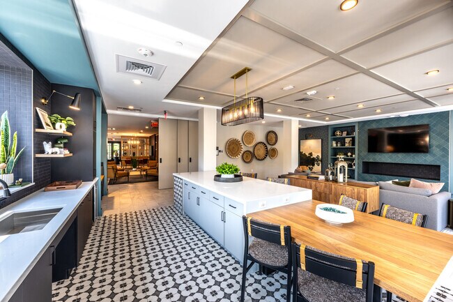 Salón de la casa club para residentes con isla de cocina y asientos de barra. - The Elmwood