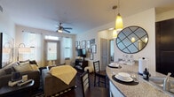 This single-floor residence offers a cohesive and functional layout with modern finishes throughout. The open-concept living and dining area is anchored by rich hardwood-style flooring, a ceiling fan, and multiple windows that invite natural light. A gallery wall adds character, while the space flows seamlessly into the dining area.

The kitchen is a standout feature, showcasing dark espresso cabinetry extending to the ceiling for ample storage, granite-look countertops, stainless steel appliances including a refrigerator and microwave, and a black range. A curved breakfast bar with pendant lighting serves as both a prep surface and casual dining spot.

The unit includes multiple bedrooms, each carpeted for comfort. The primary bedroom is generously sized with a ceiling fan, large windows with outdoor views, and room for a workspace. A secondary bedroom features a cozy layout with natural light.

Each bathroom maintains the dark cabinetry theme, paired with granite-look counters, hardwood-style flooring, and tub-shower combinations with white tile surrounds. One bedroom includes a conveniently adjacent private bathroom. The overall aesthetic is contemporary and consistent, blending warm tones with dark accents throughout.