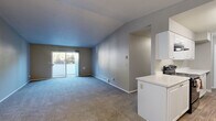 Located at 4820 NE Hazel Dell Ave in Vancouver, Washington, this 2-bedroom, 1-bathroom unit offers a well-organized single-floor layout designed for comfortable everyday living. The open-concept living room is finished with plush grey carpeting and neutral grey walls, and features a sliding glass door that fills the space with natural light while providing views of the surrounding neighborhood. A pendant light fixture marks the transition into the galley-style kitchen, which is outfitted with white cabinetry, light countertops, wood-look vinyl flooring, and black appliances including a refrigerator, electric range, and dishwasher. A peninsula adds extra prep space and reinforces the connection between the kitchen and living areas. The primary bedroom is generously proportioned, featuring dual windows that invite natural light and a baseboard heating system. A sliding double-door closet provides convenient built-in storage. The second bedroom is carpeted with neutral tones and includes its own baseboard heater. The full bathroom is clean and functional, featuring a tiled tub-shower combination and wood-look flooring. A dedicated closet adds additional storage to complete the layout.