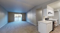Located at 4820 NE Hazel Dell Ave in Vancouver, Washington, this 2-bedroom, 1-bathroom unit offers a well-organized single-floor layout designed for comfortable everyday living. The open-concept living room is finished with plush grey carpeting and neutral grey walls, and features a sliding glass door that fills the space with natural light while providing views of the surrounding neighborhood. A pendant light fixture marks the transition into the galley-style kitchen, which is outfitted with white cabinetry, light countertops, wood-look vinyl flooring, and black appliances including a refrigerator, electric range, and dishwasher. A peninsula adds extra prep space and reinforces the connection between the kitchen and living areas. The primary bedroom is generously proportioned, featuring dual windows that invite natural light and a baseboard heating system. A sliding double-door closet provides convenient built-in storage. The second bedroom is carpeted with neutral tones and includes its own baseboard heater. The full bathroom is clean and functional, featuring a tiled tub-shower combination and wood-look flooring. A dedicated closet adds additional storage to complete the layout.