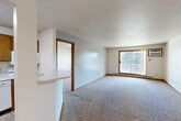Located at 5401 W 26th St in Sioux Falls, South Dakota, this two-bedroom, two-bathroom unit offers a practical and comfortable single-floor layout designed for everyday living. The open combined dining and living area is spacious and inviting, featuring plush carpeting, a ceiling fan with light fixture, and a sliding glass door that fills the room with natural light and provides direct access to a private balcony with outdoor views of surrounding trees.

The kitchen is efficiently laid out with warm oak cabinetry, white appliances including a range, over-the-range microwave, and dishwasher, along with a double-basin sink and ample counter space. A convenient pass-through bar connects the kitchen to the main living area, enhancing the open feel. Tile-style flooring runs through the kitchen and entry zones.

The generously sized primary bedroom offers wall-to-wall carpeting, a window with blinds for natural light, and a wall-mounted AC unit. The second bedroom is equally well-appointed with carpet, a window, and baseboard heating. Three closets throughout the unit provide excellent storage. Both full bathrooms feature tub-shower combinations with dark hardware accents and wood-toned vanity cabinetry. A dedicated laundry area adds convenience to this well-rounded home.