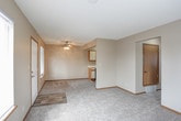 This single-floor unit offers a practical and straightforward layout designed for comfortable everyday living. The living area is carpeted in neutral-toned plush carpet and connects seamlessly to the kitchen, which is separated by a half-wall peninsula. The kitchen is equipped with black appliances, including a refrigerator and electric range, complemented by white upper cabinetry with wood accents and ample counter space. Wood-look vinyl flooring runs through the kitchen and extends into the bathrooms, providing a clean contrast to the carpeted rooms.

The bedrooms are generously sized, each featuring soft carpet, neutral wall tones, and windows fitted with horizontal blinds that allow natural light to filter in. The unit includes two full bathrooms, each outfitted with a tub-shower combination, toilet, and a vanity with a single sink and mirror. Warm-toned walls and wood-trimmed cabinetry give the bathrooms a cohesive, functional feel.

The entry foyer features a six-panel front door with wood trim, transitioning from hard-surface flooring to carpet as you move deeper into the unit. Textured ceilings are consistent throughout, and neutral beige walls provide a versatile backdrop throughout the space.