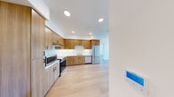 Located at 900 Chestnut St in Redwood City, CA, this two-bedroom, one-bathroom unit offers a thoughtfully designed single-level layout with a clean, modern aesthetic. Light-toned hardwood flooring runs throughout the entire space, creating a cohesive and warm atmosphere that complements the crisp white walls and contemporary finishes.

The kitchen is a standout feature, outfitted with warm wood cabinetry extending floor to ceiling, white countertops, and a full suite of stainless steel appliances including a range, microwave, dishwasher, and refrigerator. Recessed lighting illuminates the space efficiently, enhancing the functional and polished design.

Both bedrooms are well-proportioned with clean lines, white walls, and the same continuous hardwood flooring. The primary bedroom offers a comfortable footprint, while the second bedroom benefits from a large window that fills the room with natural light and provides views of the surrounding neighborhood and open sky — a bright and airy atmosphere ideal for rest or work.

The bathroom maintains the minimalist design language of the rest of the unit, featuring light wood floors, white walls, and clean fixtures. The overall layout is efficiently organized, making excellent use of the available floor area while maintaining an open and uncluttered feel throughout.