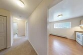 Located at 311 W Seneca St in Manlius, NY, this single-floor, one-bedroom, one-bathroom unit offers a practical and well-organized layout across a comfortable footprint. The interior is connected by two hallways that guide residents through each area of the home with ease.

The kitchen is a functional space featuring light wood cabinetry with ample storage, dark granite-style countertops, a double sink, and white appliances including a range, dishwasher, and refrigerator. A window above the counter allows natural light to brighten the room, while hardwood-style flooring and a baseboard heater add to the practical design. The kitchen opens conveniently toward the living area and hallway.

The living room offers a generously sized, open space with neutral carpeting, dual HVAC vents, and clean white walls — providing a blank canvas for personalization. The bedroom is a well-proportioned retreat finished with plush carpet, a ceiling fan with light fixture, a baseboard heater, and a window with blinds for natural light and privacy.

The bathroom includes a full-size soaking tub and shower combination with a clean white surround. A dedicated closet provides additional storage. Throughout the unit, crisp white walls, consistent flooring choices, and ceiling-mounted lighting contribute to a clean, move-in-ready atmosphere.