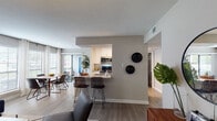 Located at 4600 University Dr in Durham, NC, this single-floor residence offers a thoughtfully designed open-concept layout that seamlessly connects the main living areas. The kitchen is a standout feature, boasting white cabinetry, granite countertops, stainless steel appliances including a refrigerator, gas range, and microwave, as well as a peninsula with bar seating — ideal for casual dining or entertaining. Light wood-look flooring flows throughout, complementing the neutral gray tones of the walls and creating a cohesive, contemporary aesthetic. The living room provides generous seating space and is bathed in natural light from large windows. A separate dining area offers additional space for meals and gatherings. The bedrooms are well-proportioned, each featuring ceiling fans, large windows with blinds, and plush area rugs. The primary bedroom suite includes direct access to a private en-suite bathroom with dual granite-topped vanities, a walk-in closet with wire shelving, and an in-unit washer and dryer — a highly practical amenity. The secondary bathroom features a tiled shower-tub combo with clean white finishes. The primary bedroom also benefits from patio access, bringing in natural light and outdoor connectivity. Overall, the space delivers a modern, comfortable living environment with functional, high-quality finishes throughout.
