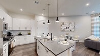 This well-appointed one-bedroom, one-bathroom residence at 630 Washington Ave in Belleville, NJ offers a thoughtfully designed single-floor layout that maximizes every square foot. The open-concept kitchen and living area serves as the heart of the home, featuring crisp white shaker cabinetry, grey quartz countertops, a mosaic tile backsplash, and a full suite of stainless steel appliances including a gas range and built-in microwave. A central kitchen island with a matte black faucet provides additional prep space and seating. The living area flows naturally from the kitchen and is anchored by large sliding glass doors that flood the space with natural light and open to an outdoor patio with greenery views. Wood-style flooring runs throughout, adding warmth and continuity. The bedroom is generously proportioned, featuring floor-to-ceiling windows overlooking a landscaped courtyard and dual built-in closets with custom shelving and hanging rods. The bathroom is finished with large-format grey tile surrounding a soaking tub and shower combination, complemented by matte black fixtures. Pendant lighting, recessed lighting, and a neutral color palette complete the modern, cohesive aesthetic of this refined residence.