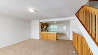 Located at 5965 Copper Beech Blvd in Kalamazoo, MI, this three-bedroom, four-bathroom multi-level home offers well-organized living space spread across three floors. The main level serves as the heart of the home, featuring an open-concept layout where a carpeted living area flows seamlessly into the kitchen. The kitchen is equipped with warm oak cabinetry, white appliances including a refrigerator, range, and built-in microwave, and an L-shaped peninsula with a light countertop. Tile flooring grounds the kitchen space, while a large window fills the area with natural light and views of surrounding greenery. A staircase with wooden balusters connects each level, adding a classic architectural touch throughout. The upper floors house the three bedrooms, including a generously sized primary bedroom with its own bathroom access, neutral carpet, and a window overlooking the outdoors. Additional bedrooms are comparably sized with carpet flooring and natural light. The four bathrooms feature oak vanities with white countertops and clean, simple finishes. Closets and hallways on multiple floors provide practical storage and circulation. The consistent use of neutral tones, warm wood accents, and carpeted bedrooms creates a cohesive and comfortable atmosphere throughout the home.