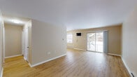 Located at 1700 Newcombtown Rd in Millville, New Jersey, this single-floor residence offers a thoughtfully laid-out living space with a clean, modern aesthetic throughout. The open-concept living area is anchored by warm-toned luxury vinyl plank flooring and neutral beige walls, creating a bright and welcoming atmosphere. A large sliding glass door floods the room with natural light and provides direct access to a private balcony, offering views of the surrounding exterior. Baseboard heating is present throughout the main living spaces.

The kitchen is a standout feature, showcasing white shaker-style cabinetry, marble-look countertops, a subway tile backsplash, and a full suite of stainless steel appliances including a refrigerator, electric range, dishwasher, and range hood. A peninsula counter provides additional prep space and casual seating potential, connecting the kitchen to the main living area.

The bedrooms are carpeted for comfort, each featuring natural light from windows with blinds and baseboard heating. The full bathroom includes a tiled shower-tub combination with clean white finishes. A hallway connects the private areas of the unit, completing a practical and comfortable floor plan ideal for everyday living.