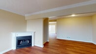 This three-floor home is thoughtfully laid out across its levels, offering a variety of functional spaces. The main living area is highlighted by warm hardwood flooring and a corner gas fireplace with a classic white mantel, complemented by crown molding and a textured ceiling that adds architectural character. The space flows openly into an adjacent room bathed in natural light from large grid-pane windows overlooking the outdoors.

The kitchen features warm-toned oak cabinetry, granite countertops, a stainless steel sink positioned beneath a window, and a dishwasher. Carpeted bedrooms are bright and comfortable, each with grid-pane windows that bring in natural light.

A full bathroom includes hardwood flooring, an oak vanity, and a tub-shower combination. Carpeted staircases with warm wood handrails connect all three floors. The lower level includes an unfinished utility area housing a furnace, water heater, and utility sink, alongside an attached garage with a roll-up door and concrete flooring, providing ample storage and parking. Together, the floors create a well-structured, functional home.