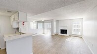This single-story, 2-bedroom, 2-bathroom home at 240 El Dorado Blvd in Houston, TX offers a well-designed open-concept layout with a bright, neutral palette throughout. The combined living and dining area is a standout feature, anchored by a classic wood-burning fireplace and bathed in natural light from large sliding glass doors and multiple windows with vertical blinds. Wood-look plank flooring flows throughout the main living areas, complementing the textured ceilings that add character to the space. The kitchen features white cabinetry, a subway tile backsplash, light stone countertops, a breakfast bar peninsula, and black appliances including a range, over-the-range microwave, and refrigerator. An in-unit laundry area is conveniently located just off the kitchen. The primary bedroom is generously sized with sliding glass door access, a ceiling fan, plush carpet, and a spacious walk-in closet equipped with wire shelving. The second bedroom also enjoys ample natural light and carpet flooring. Both bathrooms are finished with white cabinetry, stone countertops, framed mirrors, and tub-shower combinations with clean white tile surround. A hallway connects the bedrooms with four closets providing excellent storage throughout.