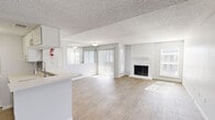 This single-story, 2-bedroom, 2-bathroom home at 240 El Dorado Blvd in Houston, TX offers a well-designed open-concept layout with a bright, neutral palette throughout. The combined living and dining area is a standout feature, anchored by a classic wood-burning fireplace and bathed in natural light from large sliding glass doors and multiple windows with vertical blinds. Wood-look plank flooring flows throughout the main living areas, complementing the textured ceilings that add character to the space. The kitchen features white cabinetry, a subway tile backsplash, light stone countertops, a breakfast bar peninsula, and black appliances including a range, over-the-range microwave, and refrigerator. An in-unit laundry area is conveniently located just off the kitchen. The primary bedroom is generously sized with sliding glass door access, a ceiling fan, plush carpet, and a spacious walk-in closet equipped with wire shelving. The second bedroom also enjoys ample natural light and carpet flooring. Both bathrooms are finished with white cabinetry, stone countertops, framed mirrors, and tub-shower combinations with clean white tile surround. A hallway connects the bedrooms with four closets providing excellent storage throughout.