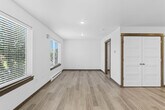 Located at 1110 Rosa Way in Bozeman, Montana, this single-floor studio makes smart use of its compact footprint through a thoughtful, open-concept layout. Light wood-tone flooring runs throughout, complementing the crisp white walls and recessed lighting to create a clean, modern aesthetic.

The combined living, dining, and kitchen area forms the heart of the space. Large windows fitted with horizontal blinds line the living area, flooding the room with natural light and offering views of the surrounding greenery and neighborhood. Baseboard heating and a wall-mounted AC unit ensure year-round comfort.

The kitchen is well-appointed with white shaker-style cabinetry, dark countertops, a full suite of stainless steel appliances including a refrigerator, electric range, microwave, and dishwasher, and a single-basin sink. A dedicated in-unit laundry closet with warm wood-trimmed framing houses a full-size washer and dryer, conveniently tucked adjacent to the kitchen.

The bathroom features light wood-tone flooring, a combined tub and shower with a sliding glass enclosure, a vanity with dark countertop and brushed nickel hardware, and a baseboard heater. A separate closet provides additional storage. The entry door features a modern keypad lock set within a warm wood frame, adding a practical and stylish finishing touch.