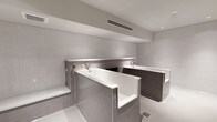 This meticulously designed bathroom space presents a refined, spa-like aesthetic defined by a cohesive neutral palette and high-quality finishes throughout. The single-level layout is anchored by two deep soaking tubs, each encased in grey subway tile surrounds that serve as a defining architectural element. Wall-mounted chrome fixtures accompany each tub, contributing to the clean, uncluttered design language.

The walls feature a combination of large-format light grey tiles and smaller mosaic stone tiles, visible through a sleek black-framed glass partition that delineates a separate wet area. This partition adds a contemporary architectural detail while maintaining a sense of openness. A built-in tiled bench provides a functional and elegant seating element within the wet zone.

The flooring is finished in a speckled light grey material that complements the surrounding tile work. Recessed ceiling lights and a linear HVAC vent are integrated cleanly into the smooth ceiling, ensuring both comfort and a streamlined appearance. The overall ambiance is calm and minimalist, evoking a high-end wellness environment with careful attention to material consistency and spatial flow.