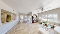 Located at 9620 W Russell Rd in Las Vegas, NV, this single-story 2-bedroom, 2-bathroom residence offers a thoughtfully designed open-concept layout finished with light wood-look flooring throughout the main living areas. The spacious living room is bright and airy, benefiting from natural light through large windows and a ceiling fan overhead, creating a comfortable and inviting atmosphere. It flows seamlessly into a dedicated dining area with sliding glass door access, enhancing the sense of openness. The galley-style kitchen is well-equipped with white cabinetry, white quartz countertops, stainless steel appliances including a refrigerator, range, microwave, and dishwasher, complemented by a classic subway tile backsplash. The generously sized primary bedroom features plush carpet, a ceiling fan, a walk-in closet, and a private en-suite bathroom. The second bedroom also includes carpet flooring, a ceiling fan, and its own closet. Both bathrooms are clean and functional, with the full bath offering a soaking tub and shower combination. Additional highlights include three closets throughout, a dedicated laundry room with washer hookups and wire shelving, and a textured ceiling detail across the home.