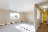 Located at 10623 E Exposition Ave in Aurora, CO, this single-floor residence offers three bedrooms and one bathroom within a thoughtfully arranged layout. The living room is a standout space, bathed in natural light streaming through large windows that offer outdoor views. Soft carpet flooring runs throughout, complemented by neutral beige walls that create a warm, cohesive atmosphere. A wall-mounted A/C unit and baseboard heaters ensure year-round comfort. The living area connects seamlessly to the kitchen via a convenient pass-through window, where white cabinetry and white appliances — including a range and refrigerator — provide a clean, functional cooking space with hardwood-style flooring. The spacious primary bedroom is generously sized, featuring a ceiling fan, a built-in closet with shelving, and a charming French door. Additional bedrooms are carpeted with natural light and baseboard heating. The bathroom features full tile surround with a bathtub. The floor plan flows efficiently, making excellent use of every square foot in this practical and comfortable Aurora home.