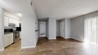 This single-floor residence offers a well-organized layout with a clean, neutral aesthetic throughout. The open living and dining area is finished with wood-look flooring and painted in soft gray tones, creating a cohesive and inviting atmosphere. Natural light streams in through a large sliding glass door fitted with vertical blinds, offering easy access to the outdoors. A pass-through window connects the living and dining space to the kitchen, which features white cabinetry, dark speckled countertops, and stainless steel appliances including a refrigerator and range. A louvered closet door provides convenient pantry storage within the kitchen area. The bedrooms are carpeted for comfort and each benefits from windows that bring in natural light. Both bathrooms share a consistent design, each appointed with wood-look flooring, a tub-shower combination with white tile surround, a vanity with dark speckled countertops, white cabinetry, and a large mirror. Textured ceilings are found throughout the living spaces, adding a classic touch to the interior. The unit also includes a closet near the entry and a functional hallway connecting the living areas to the private rooms, offering a practical and comfortable single-level living experience.