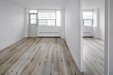 Located on the 24th floor at 45 Dunfield Ave in Toronto's Midtown neighbourhood, this 2-bedroom, 1-bathroom unit offers a compact yet efficiently arranged layout. Throughout the unit, light-toned hardwood-style flooring creates a clean, cohesive aesthetic against bright white walls, contributing to an airy and well-lit ambiance.

The entrance leads into the main living area, which connects to a galley-style kitchen outfitted with white cabinetry featuring brushed nickel hardware, a neutral quartz-toned countertop, stainless steel appliances including a refrigerator and stove, and a single-basin undermount sink. A louvred door separates the kitchen from the living space.

The spacious primary bedroom receives generous natural light through large windows framing urban skyline views, and includes a baseboard heating unit beneath the sill. The second bedroom, while more compact, maintains the same clean finishes and connects conveniently to the rest of the unit.

The bathroom is finished with white tile, a soaker tub with shower, a vanity with a taupe countertop, and a mirrored medicine cabinet. Additional features include an in-unit intercom system and a dedicated closet. The overall atmosphere is bright, modern, and functional.