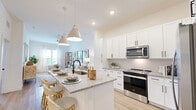 Located in Jacksonville, FL, this thoughtfully designed one-bedroom, one-bathroom residence offers a bright and cohesive living experience across a single floor. The open-concept layout seamlessly connects the kitchen and living room, creating a functional yet inviting space. The kitchen is a standout feature, showcasing crisp white shaker cabinetry, granite countertops, a subway tile backsplash, and stainless steel appliances including a range, over-the-range microwave, and refrigerator. A central island with seating and stylish cone pendant lighting serves as both a prep space and a casual dining area. Light wood-tone flooring flows throughout the main living areas, enhancing the sense of warmth and continuity. The living room is filled with natural light from large windows dressed in sheer curtains, complemented by a ceiling fan overhead. The bedroom offers a serene retreat with plush carpeting and a calming accent wall. The bathroom features a granite-topped vanity with white cabinetry, black hardware accents, and a full tub-shower combination with white tile surround. A dedicated closet provides practical storage. The overall ambiance is clean, modern, and bright — ideal for comfortable everyday living.