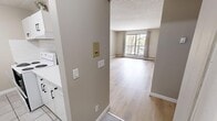 This 2-bedroom, 1-bathroom unit in Calgary, AB offers a practical and thoughtfully arranged single-floor layout. Light-toned laminate flooring runs throughout the space, complemented by neutral warm-grey walls and textured ceilings, creating a clean and cohesive aesthetic.

The living area is bright and open, anchored by a large window with views of surrounding trees, allowing generous natural light to fill the room. A hallway connects the main living areas to the bedrooms, providing a clear and functional flow through the unit.

Both bedrooms are comfortably sized with windows that frame leafy outdoor views, baseboard heating, and built-in closets featuring dark-toned bifold doors that add a subtle contrast to the light interior palette. The primary bedroom offers a generous footprint with ample room for furnishings.

The bathroom is efficiently designed, featuring a wood-toned vanity with a single sink and storage cabinetry below, a large mirror with overhead lighting, and a full bathtub and shower combination. The laminate flooring extends into this space, maintaining consistency throughout.

A dedicated entry hallway with adjacent cabinetry and in-unit laundry access adds to the overall convenience of this straightforward and functional unit, well-suited for those seeking a comfortable home base in Calgary.