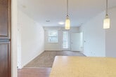 Located at 12330 Vivian Adams Dr in Waldorf, MD, this 3-bedroom, 2-bathroom home offers a thoughtfully designed layout across a single primary living floor. The open-concept main area seamlessly integrates the living room, dining room, and kitchen, creating a welcoming, connected space. The kitchen is a standout feature, showcasing rich dark wood cabinetry, a light stone-look countertop island with pendant lighting, wood-look flooring, and black appliances including a refrigerator, range, microwave, and dishwasher. The living and dining area transitions to plush carpeting and is brightened by natural light from a large window and a glass door leading to a private balcony. The three bedrooms are carpeted and well-lit, with the generously sized primary bedroom offering ample space and dedicated closet storage. Four closets throughout provide abundant storage. The two bathrooms feature tile flooring, dark wood vanities, and a tub-shower combination. A dedicated laundry area and a connecting hallway complete the functional layout. Clean white walls and consistent finishes lend the home a bright, cohesive aesthetic throughout.