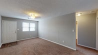 This 2-bedroom, 2-bathroom garden-style residence is thoughtfully laid out across a single floor, offering a comfortable and functional living environment. The spacious living room features warm, neutral-toned carpeting, soft gray walls, and a ceiling fan with integrated lighting, creating a welcoming and well-ventilated space. A dedicated entryway with a paneled front door provides a clean transition into the main living area.

The kitchen is outfitted with a full suite of black Frigidaire appliances, including a refrigerator, electric range, and dishwasher. Cabinetry with wood-trim accents frames the space, complemented by light countertops, a double-basin sink, and durable wood-look flooring that extends throughout the kitchen and into the bathrooms.

Both bedrooms are generously proportioned, featuring the same plush carpeting and neutral gray wall tones as the living room. Ceiling fans with lighting fixtures are present in the bedrooms, and natural light filters in through windows with blinds. One bedroom also includes an electrical panel for added utility access.

Each bathroom is equipped with a single-vanity, a tub-shower combination, and wood-look flooring that ties the wet areas together cohesively. The textured ceilings are consistent throughout the unit, contributing to a uniform and classic interior aesthetic overall.