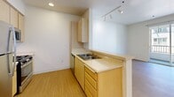 Located at 4161 Keegan St in Dublin, CA, this one-bedroom, one-bathroom unit offers a thoughtfully designed single-floor layout that maximizes its compact footprint. The kitchen is a standout feature, equipped with stainless steel appliances including a refrigerator, gas range, and microwave, complemented by light wood cabinetry, light stone countertops, and recessed lighting. A peninsula with a built-in sink and additional counter space creates an open flow into the living area, which features light wood-style flooring and track lighting. Sliding glass doors lead to a private balcony, bringing in natural light and outdoor views. The bedroom is carpeted for comfort and features a window overlooking the exterior, allowing for ample natural light. A six-panel door and neutral wall tones complete the room's clean, simple aesthetic. The bathroom includes a soaking tub and shower combination with a safety grab bar, a warm wood-toned vanity, and light hardwood-style flooring, maintaining the unit's cohesive design language. Throughout, the space features a clean, modern palette of white walls, light wood tones, and neutral finishes, creating a bright and functional living environment.