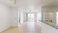 Located in Homestead, FL, this 2-bedroom, 2-bathroom residence offers a clean, functional layout with tile flooring throughout. The kitchen is a standout feature, showcasing rich dark-wood cabinetry extending to the ceiling, granite countertops, a double stainless steel sink, and black appliances including a refrigerator, electric range, microwave, and dishwasher. Track lighting adds a modern touch to this well-appointed space.

Both bedrooms are bright and comfortably sized, each outfitted with ceiling fans and windows that frame lush tropical greenery. The primary bedroom includes a spacious double sliding-door closet, providing ample storage. The second bedroom benefits from dual windows, filling the room with abundant natural light. A sliding glass door in the main living area opens to a balcony overlooking palm trees, bringing the Florida outdoors in.

The two bathrooms are finished consistently with tile flooring and tile-surround tub-shower combinations. One bathroom features dark-wood vanity cabinetry with a granite countertop and a large mirror. Both are clean and efficiently designed. The crisp white walls and light tile floors throughout lend the home a bright, airy feel well-suited to South Florida living.