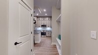 This well-designed 710 square foot apartment maximizes space and functionality. The single-floor layout includes one bedroom, measuring 160 square feet, and two bathrooms, offering convenience and privacy. The heart of the home is an open-concept kitchen and living room area, perfect for entertaining or relaxing.

The space boasts modern finishes, as evidenced by the sleek laminate flooring visible in the image. Large windows, including a sizable one in the living area, flood the apartment with natural light and provide views of the surrounding urban landscape. The neutral wall color enhances the sense of spaciousness and light.

A notable feature is the glass-paned door, likely leading to a small balcony or patio, further extending the living space. Recessed lighting in the ceiling adds to the contemporary feel while providing adjustable illumination.

The apartment's efficient layout includes a separate laundry area, a hallway for improved flow, and an entrance foyer. Despite its compact size, the thoughtful design ensures each square foot is utilized effectively, creating a comfortable and functional urban dwelling.