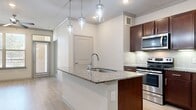 This thoughtfully designed 2-bedroom, 1-bathroom home offers a comfortable and functional layout across a single floor. The open-concept kitchen and living area serves as the heart of the home, anchored by a granite-topped island with a built-in sink and stylish pendant lighting overhead. Rich dark wood cabinetry, a subway tile backsplash, and a full suite of stainless steel appliances — including a refrigerator, range, and microwave — complete the kitchen. Light wood-style flooring flows throughout the main living areas, complemented by crown molding and recessed lighting that add a refined touch.

The living room is generously sized, featuring a ceiling fan, built-in desk area, and easy access to the rest of the home via a connecting hallway. Both bedrooms are carpeted for comfort, each offering a ceiling fan and a large window that invites natural light and outdoor views. The spacious primary bedroom connects to a well-sized walk-in closet outfitted with wire shelving systems for ample storage.

The bathroom features a dual-sink vanity with granite countertops, dark wood cabinetry, framed mirrors, and tile flooring, offering both practicality and style. A second closet provides additional storage, rounding out this well-organized and move-in ready home.
