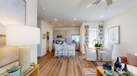 Located at 8925 Livingo Way in Kissimmee, Florida, this two-story home offers a thoughtfully designed layout spread across two floors. The main floor is notably expansive, housing an open-concept living, dining, and kitchen area filled with natural light from large windows. The kitchen is well-appointed with gray shaker-style cabinetry, granite countertops, a subway tile backsplash, stainless steel appliances, and a central island with bar seating — ideal for both everyday living and entertaining. Warm wood-look flooring flows throughout the main level, complementing the bright, neutral color palette. A dedicated den on the main floor provides a flexible space suitable for a home office or study. A full bathroom and laundry room round out the first floor's functionality. Upstairs, two carpeted bedrooms offer comfortable retreats, each with windows that bring in natural light and neighborhood views. The primary bedroom includes its own closet and an en-suite bathroom featuring a glass-enclosed walk-in shower with white subway tile and granite-topped vanity. A second full bathroom serves the additional bedroom. Outside, the home features a private, white vinyl-fenced backyard with a grassy area, offering a secluded outdoor space under the sunny Florida sky.