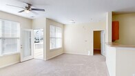 Located at 327 Guinevere Ln in Wilmington, NC, this well-appointed one-bedroom, one-bathroom residence offers a thoughtfully designed single-floor layout. The living area is bright and welcoming, featuring soft carpet flooring, warm neutral walls, a ceiling fan, and multiple windows with blinds that fill the space with natural light. A glass-paneled door opens directly to a private balcony, extending the living space outdoors. The kitchen is efficiently laid out with light wood cabinetry, light-colored countertops, tile flooring, and a full suite of black appliances including an electric range, over-the-range microwave, refrigerator, and dishwasher. A utility room is conveniently accessible from the kitchen. The bedroom is a comfortable, carpeted retreat with two windows that bring in ample natural light. A dedicated walk-in closet features floor-to-ceiling wire shelving and hanging rods, providing generous storage. A separate entry closet with a hanging rod adds additional storage flexibility. The space maintains a clean, neutral palette throughout, creating a bright and move-in-ready atmosphere ideal for easy personalization.