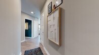 This single-floor residence in Secaucus, NJ offers a thoughtfully designed open-concept layout with contemporary finishes and a cohesive modern aesthetic. The entryway hallway is lined with light gray walls, wood-look flooring, and curated wall art, setting an inviting tone from the moment you enter.

The kitchen is well-appointed with gray shaker-style cabinetry, a classic white subway tile backsplash, stainless steel appliances including a gas range and French door refrigerator, and a central island with a clean white countertop. It flows seamlessly into the living and dining area, which is brightened by a bank of large windows offering open outdoor views. The living space features rich dark accent walls, layered textiles, and pendant lighting that create a warm, contemporary ambiance.

A dedicated room with deep teal walls and hardwood flooring serves as a striking flex space, ideal for a home office or study. The primary bathroom features a dual-sink floating vanity with warm wood cabinetry, a backlit mirror, and a tiled shower surround. A secondary bathroom offers gray cabinetry, a white countertop, and a tub-shower combination. The bedroom includes a bright window with outdoor views and wood-look flooring throughout.