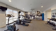 Located at 3443 Park St in Grove City, Ohio, this single-floor fitness facility is thoughtfully designed to support a comprehensive workout experience. The space is divided into two distinct zones, seamlessly connected by sleek, dark-framed glass doors that lend a modern, professional aesthetic to the interior.

The main cardio and equipment room is generously proportioned, featuring durable rubber flooring, recessed lighting, and a ceiling fan that promotes air circulation during workouts. Large windows with roller shades line the walls, filling the space with natural light and offering views of the surrounding outdoors. The room is outfitted with multiple treadmills, elliptical machines, a stationary bike, and a weight bench, among other equipment. A bold black-and-white athletic-themed photo mural adorns one wall, adding dynamic visual energy to the space.

The adjacent studio room offers a clean, open layout with light hardwood-style flooring, a tray ceiling with recessed lighting, and floor-to-ceiling mirrors along one wall. Fixed and freestanding ballet barres, TRX suspension straps, and large windows make this room ideal for yoga, barre, stretching, or group fitness classes. Motivational text is subtly incorporated into the mirror wall, reinforcing an encouraging atmosphere throughout this well-appointed fitness center.