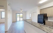 Located along S Dixie Highway in Homestead, FL, this one-bedroom, one-bathroom unit offers a well-designed single-floor layout with a clean, modern aesthetic. The open-concept kitchen and living area is the heart of the unit, featuring light wood-look flooring, a ceiling fan, and sliding glass doors that lead to a private balcony with scenic outdoor views of the surrounding landscape. The kitchen is equipped with black appliances including an electric range, built-in microwave, and refrigerator, complemented by light wood cabinetry, white subway tile backsplash, and granite countertops with an integrated sink. The bedroom is a bright and comfortable space with light-toned hardwood-style flooring, crisp white walls, and a large window framing views of palm trees and greenery. Three closets provide ample storage throughout the unit. The bathroom features a granite-topped vanity with wood cabinetry, large-format light tile flooring, and a full soaking tub with a tiled surround and curved curtain rod. Additional spaces include a laundry area, utility room, and hallway, rounding out a thoughtfully organized and functional floor plan with a fresh, contemporary feel.
