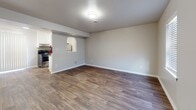 Located at 4017 Cabin Creek Court in Hopewell, Virginia, this two-story home offers a straightforward, functional layout distributed across two levels connected by a staircase. The main level features open living and dining areas finished with durable wood-look plank flooring in a warm, medium-toned finish. Natural light enters through blinded windows, and a front entry door opens directly into the main living space. A charming arched pass-through connects the living and dining area to the kitchen, which is equipped with white cabinetry, warm-toned countertops, a stainless steel refrigerator, and a gas range. Light wood-look flooring continues throughout the kitchen.

A utility area on the main level houses a stacked washer and dryer unit alongside a water heater and HVAC system, providing convenient in-unit laundry access. The upper level contains the bedrooms, each finished with neutral wall-to-wall carpeting. One bedroom features dual windows for added natural light, while another includes a closet with built-in shelving. The full bathroom on the upper level is appointed with a single-sink vanity with white cabinetry, a toilet, and a tub-shower combination, all finished with wood-look flooring. The overall palette throughout the home is neutral and clean, lending a bright, move-in ready atmosphere.