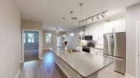 Located at 3234 North Scottsdale Road in Scottsdale, Arizona, this single-floor, two-bedroom residence offers a thoughtfully organized layout that maximizes every square foot. The open-concept kitchen and living area serves as the heart of the home, anchored by a large central island with a sparkling quartz countertop, an integrated sink, and stylish globe pendant lighting. The kitchen features white shaker cabinetry, stainless steel appliances including a gas range, built-in microwave, and a full-size refrigerator, complemented by track lighting and light wood-tone flooring that runs throughout. The living area flows seamlessly from the kitchen, with a ceiling fan and natural light streaming through windows that overlook the outdoors. Both bedrooms are carpeted for comfort, with the primary bedroom offering generous proportions, a ceiling fan, and windows with outdoor views. The second bedroom also benefits from easy access to a bathroom and the kitchen area. Two closets provide ample storage, while a dedicated laundry space and a private patio round out the functional amenities. Neutral wall tones and clean white trim throughout create a bright, cohesive aesthetic well-suited to the Scottsdale lifestyle.