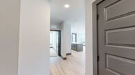 This well-appointed 2-bedroom, 2-bathroom residence is thoughtfully designed across a single floor, offering a clean, modern aesthetic throughout. The open-concept kitchen and living area serves as the heart of the home, anchored by a substantial gray island with a bright white countertop and pendant lighting overhead. The kitchen is equipped with stainless steel appliances, white upper cabinetry, and a subway tile backsplash, all complemented by light hardwood flooring that flows seamlessly through the main living spaces. Large windows fitted with horizontal blinds invite generous natural light into the living area, which also features access to an outdoor space. The primary bedroom is a comfortable retreat with plush carpeting, a ceiling fan, and windows offering outdoor views. It is accompanied by a walk-in closet featuring wire shelving. The primary bathroom is well-appointed with a dual-sink granite vanity, matte black hardware, framed mirrors, and a glass-enclosed shower. The second bedroom also features soft carpeting and ample wall space, while the second bathroom mirrors the refined design with a granite vanity, matte black fixtures, and hardwood-style flooring. A hallway connects the spaces with clean transitions, completing this cohesive and modern layout.