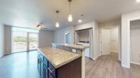 Located at 4602 Cottage Grove Rd in Madison, WI, this single-floor unit offers a thoughtfully designed open-concept layout that seamlessly connects the kitchen, dining, and living areas. The kitchen is a standout feature, equipped with dark espresso cabinetry, granite-look countertops, black appliances including a refrigerator, range, microwave, and dishwasher, and a central island with pendant lighting overhead. Recessed lighting and wood-look flooring throughout the main living areas add to the clean, modern aesthetic. The living room is bright and welcoming, with large sliding glass doors that open to a private balcony offering outdoor views, complemented by a ceiling fan for added comfort. The bedroom features plush carpeting and a generously sized walk-in closet outfitted with a wire shelving organization system. A dedicated in-unit laundry area provides added convenience. The bathroom is finished with dark cabinetry matching the kitchen, a wide vanity with a large mirror, and wood-look flooring. Neutral wall tones and consistent finishes throughout create a cohesive and functional living environment.