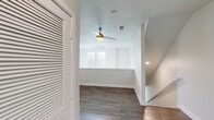 Located in the desirable Steiner Ranch community of Austin, TX, this well-appointed two-story home offers three bedrooms and three bathrooms across two thoughtfully laid-out floors. The main level features an open-concept kitchen and living area with rich hardwood-style flooring. The kitchen is a standout, boasting a large center island with pendant lighting, stainless steel appliances including a refrigerator and range, white cabinetry, and recessed lighting — ideal for both cooking and entertaining. Upstairs, the secondary living room features vaulted ceilings, a ceiling fan, and the same warm hardwood-style flooring. The bedrooms are carpeted and comfortable, each equipped with ceiling fans and closets. Secondary bedrooms share a clean, tiled bathroom with a soaking tub and tiled surround. The spacious primary bedroom includes a walk-in closet outfitted with built-in shelving and an en-suite bathroom featuring a dual-sink vanity with dark countertops and elegant wall sconces. A private balcony off the upper level offers serene views of the surrounding Texas Hill Country greenery. The attached garage provides additional convenience and storage. Throughout, the home maintains a clean, neutral palette with modern finishes.