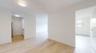 Located at 2470 Southvale Crescent in Ottawa's east end, this two-bedroom, one-bathroom unit offers a well-organized single-floor layout designed for comfortable everyday living. Light-toned hardwood-style flooring runs consistently throughout the space, complementing the crisp white walls and creating a clean, cohesive aesthetic.

The living room is a generously proportioned area with open sightlines and a baseboard heating unit, providing a comfortable and versatile space for everyday use. Natural light filters in through a window offering views of the surrounding neighbourhood's mature greenery. The galley-style kitchen is efficiently designed, featuring white cabinetry with modern hardware, white countertops, a black electric range, and a stainless steel refrigerator—maximizing function within a compact footprint.

The primary bedroom is a well-sized private retreat, while the second bedroom offers flexible use as a guest room or home office. Both rooms maintain the same light flooring and neutral white walls found throughout the unit. The bathroom is finished with white tile walls, a full tub-shower combination with chrome fixtures, and tile flooring, presenting a clean and functional design. Overall, the unit delivers a bright, minimalist atmosphere well-suited for modern living.